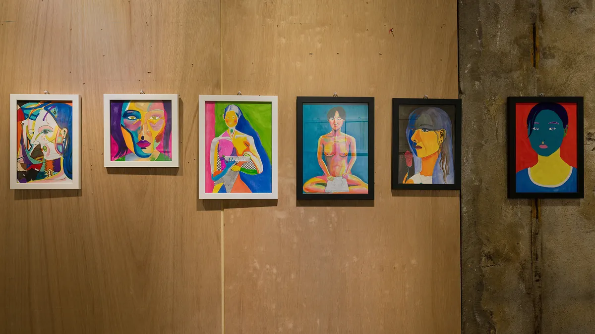Installation view — row of colorful portrait paintings